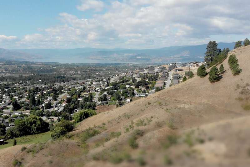 View of a city from the hillside with mountains in the background